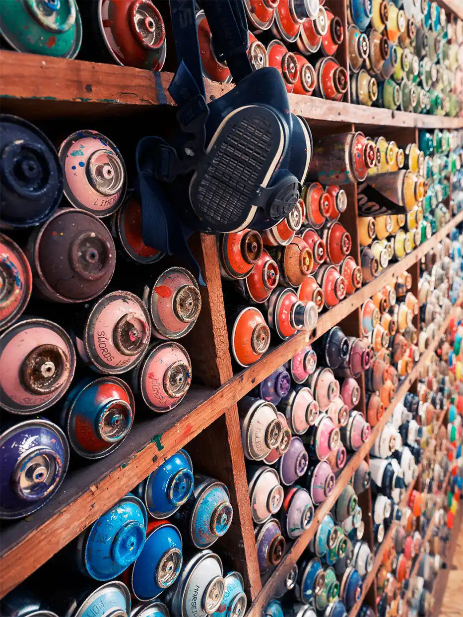 Bouteilles de peinture en spray colorées sur une étagère.